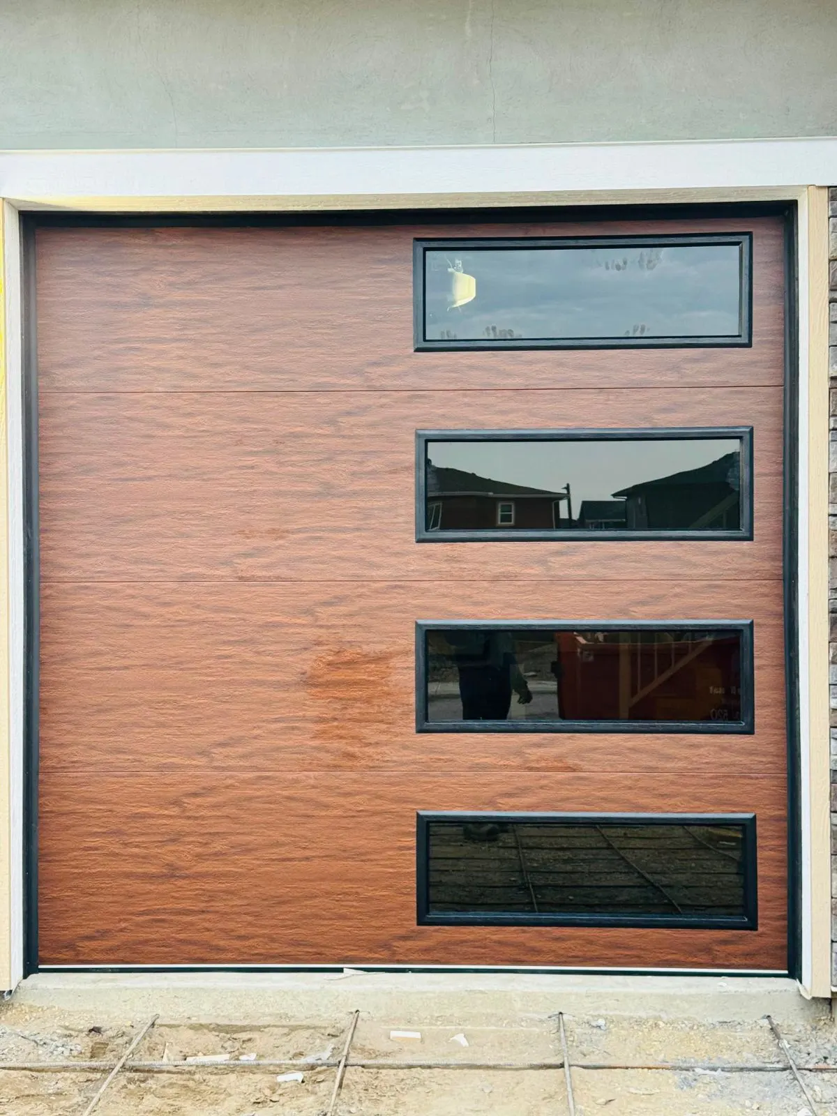 A mahogany woodgrain garage door with a column of windows, installed by Eagle Garage Doors