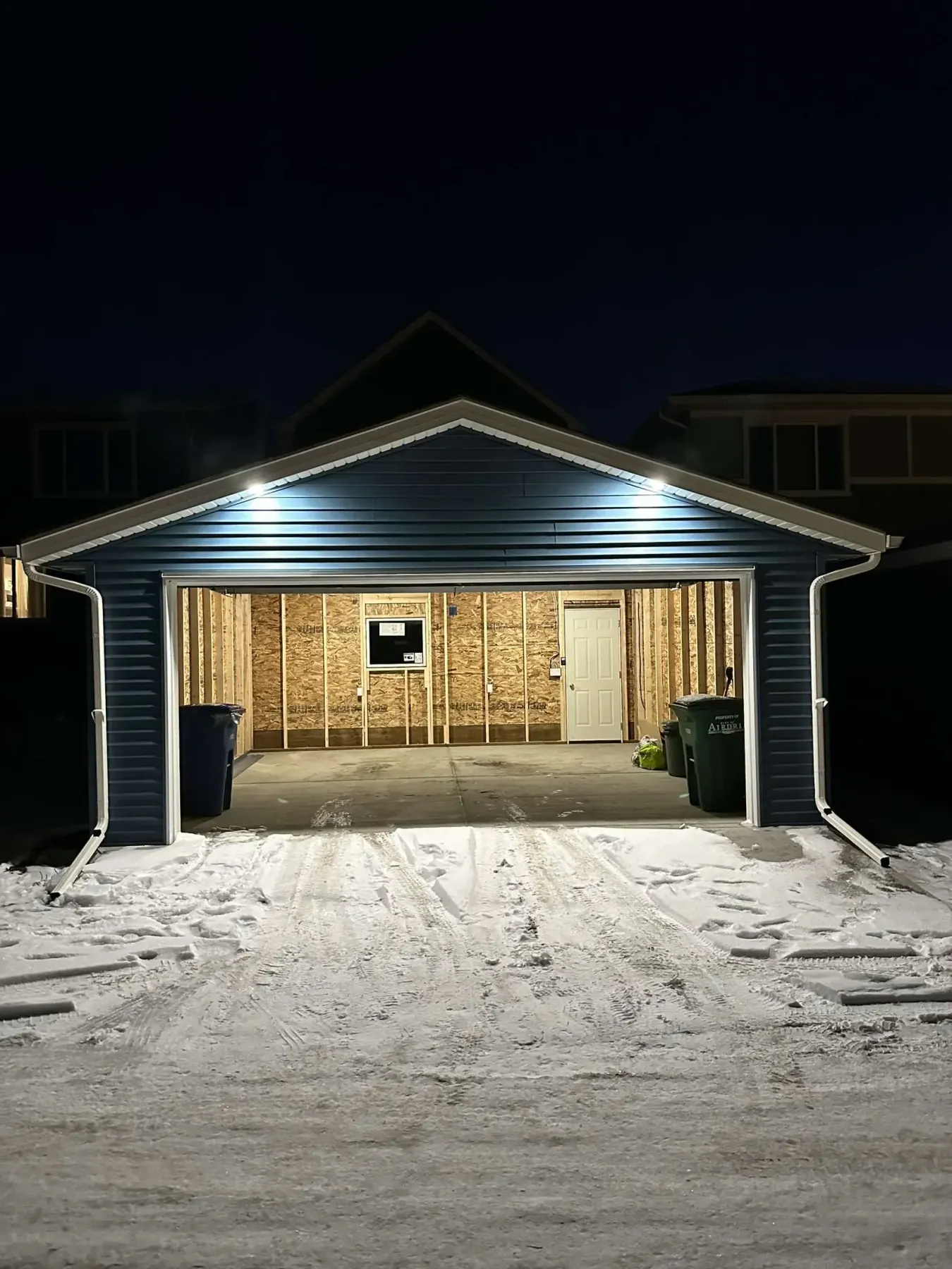 A new detached garage by Pama Homes, open and lit at night